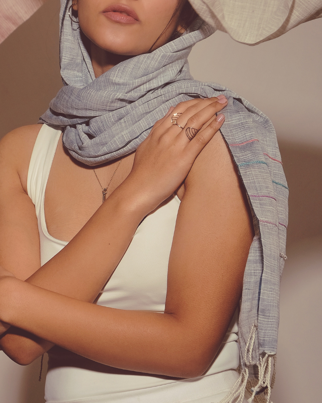 Woman wearing a blue embroidered scarf with a neutral background