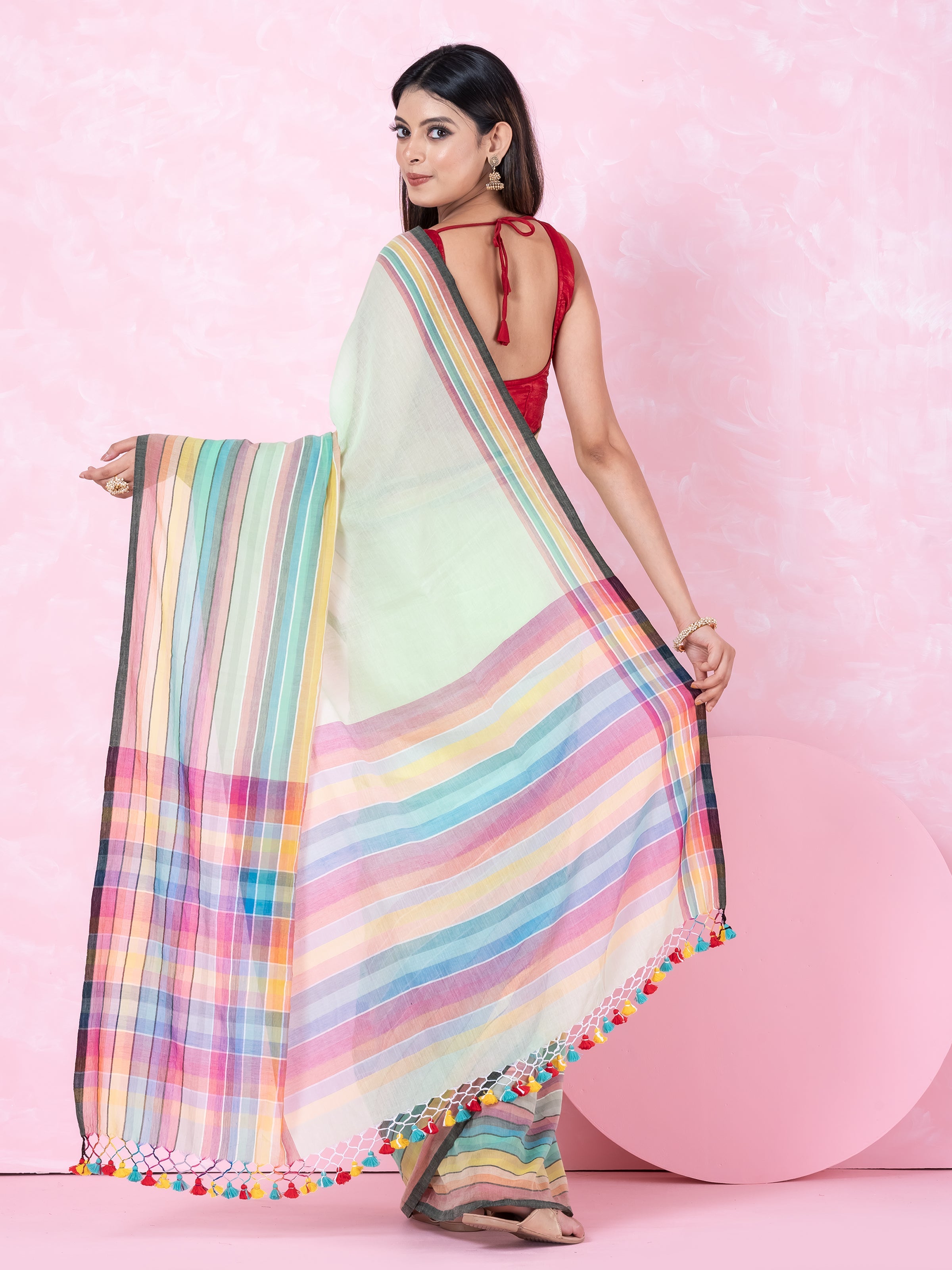 A woman modeling a traditional saree with a sea green body and multicolored block stripes by Shopaame, with a red blouse piece.