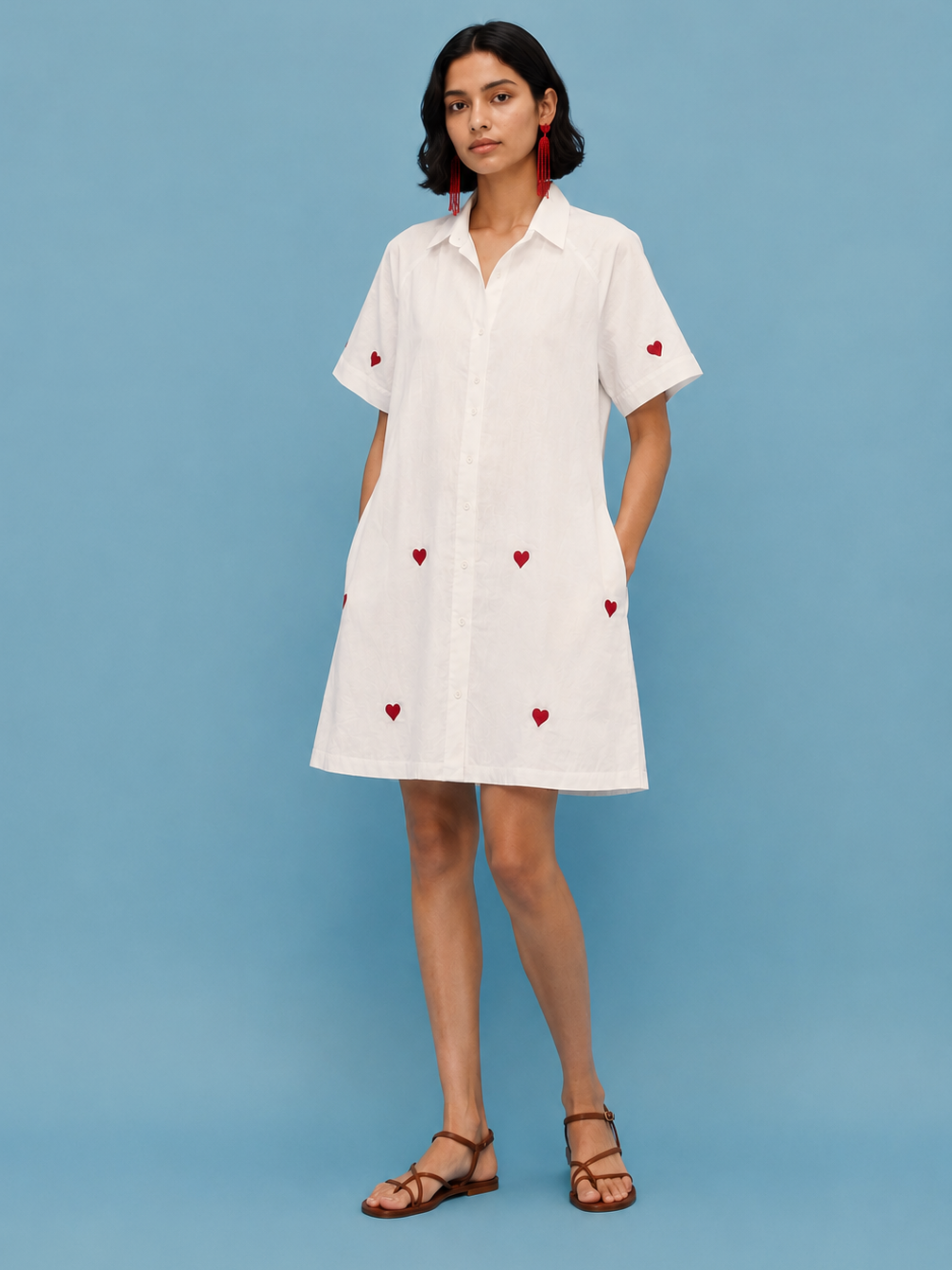 Model wearing Luna Mini Dress in off-white cotton linen featuring red heart embroidery, raglan sleeves, button-front closure, and a relaxed A-line silhouette.