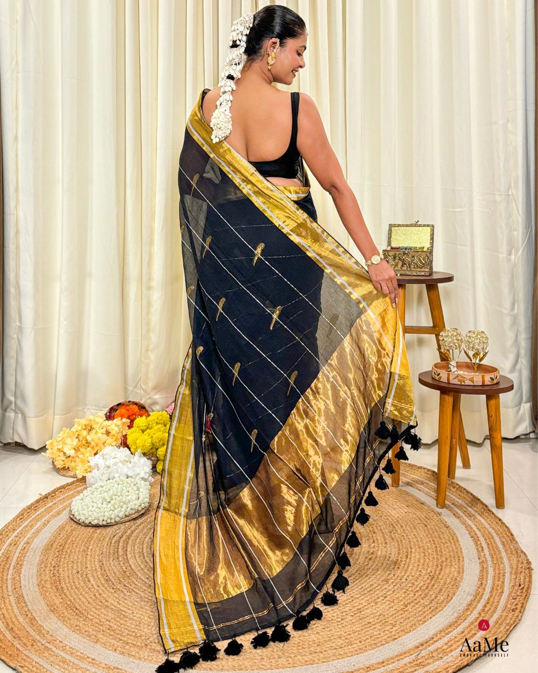 Women wearing handcrafted black mulmul cotton saree with golden border, styled for festive and cultural occasions