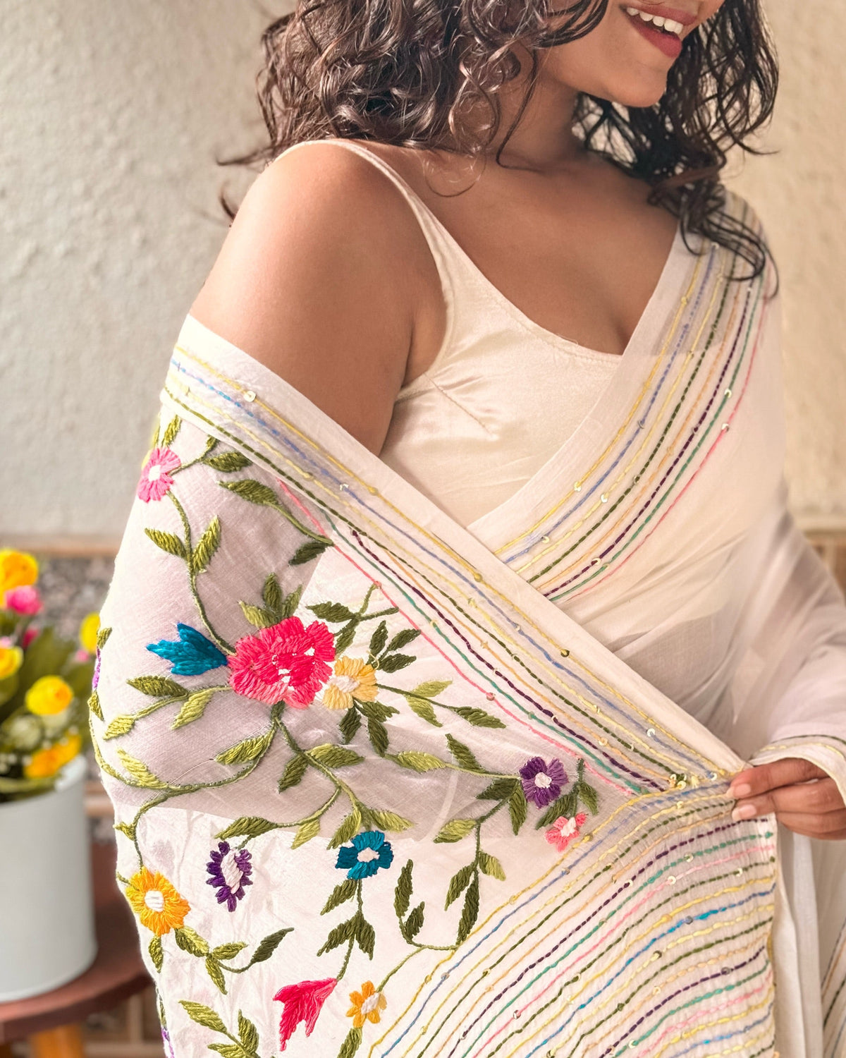 Elegant white embroidered saree with intricate floral thread work and soft graceful drape