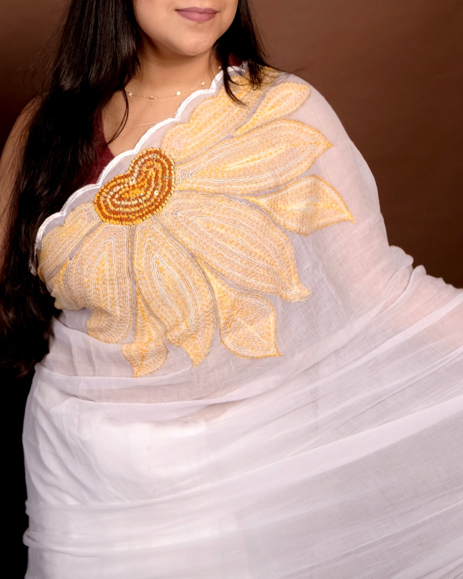 Lightweight white embroidered mulmul cotton saree with sunflower detailing, perfect for festive wear and warm days.