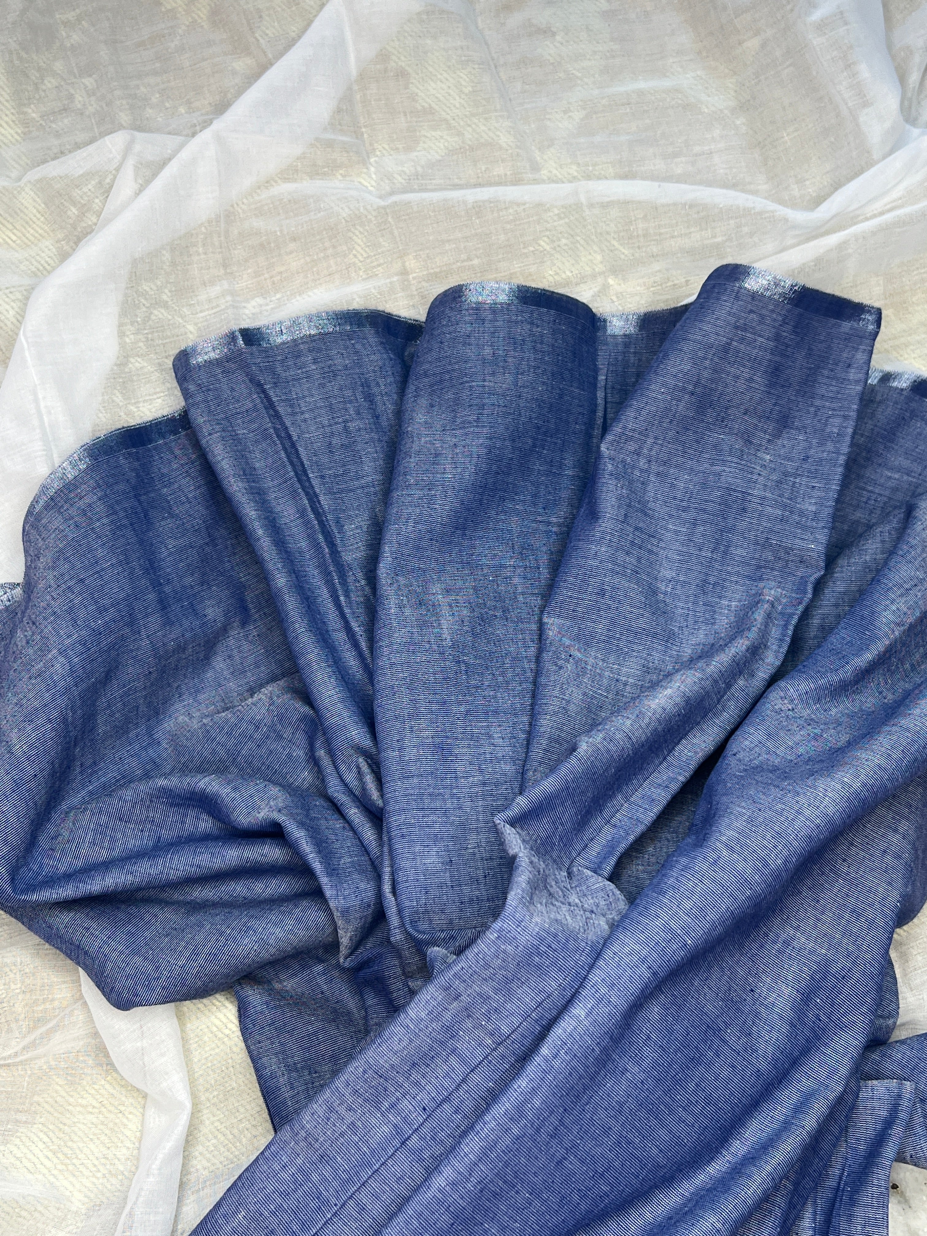 A khaadi cotton Shopaame saree showcasing a powder blue color with a silver border and simple border with pompom finishing at the end.
