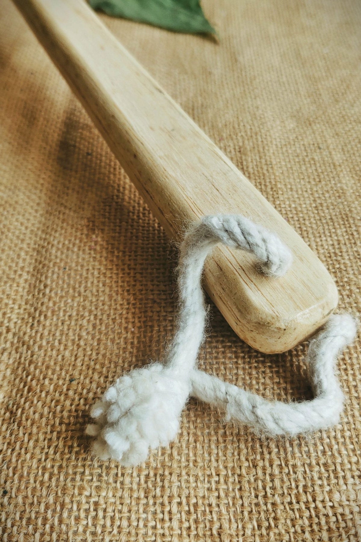 Eco-friendly natural back scrubber with long bamboo handle and soft cotton loop, placed on a jute fabric background — ideal for zero-waste skincare and sustainable bathing routines.