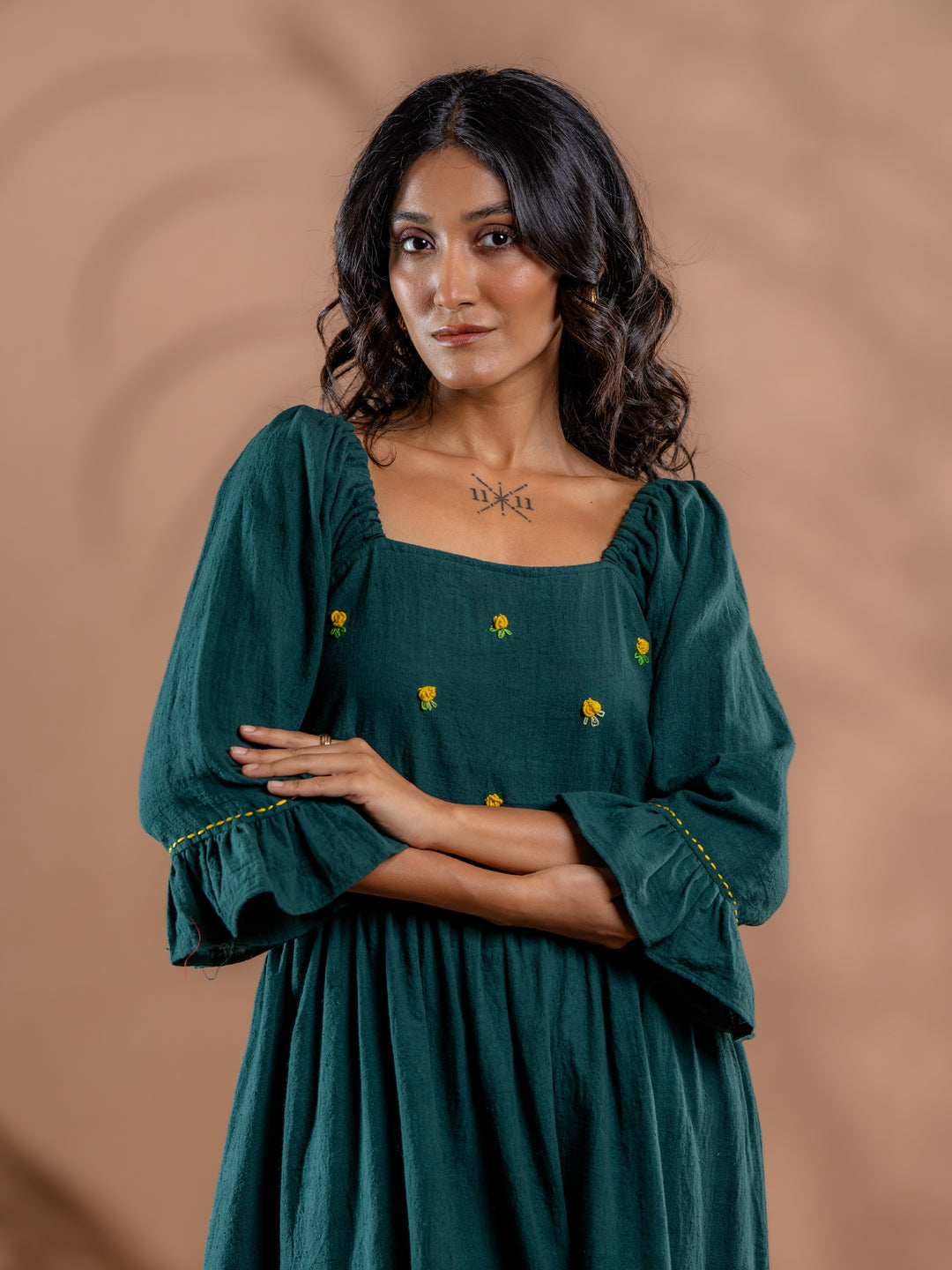 Close up of hand embroidery floral details and neck line details on teal green cotton tunic dress