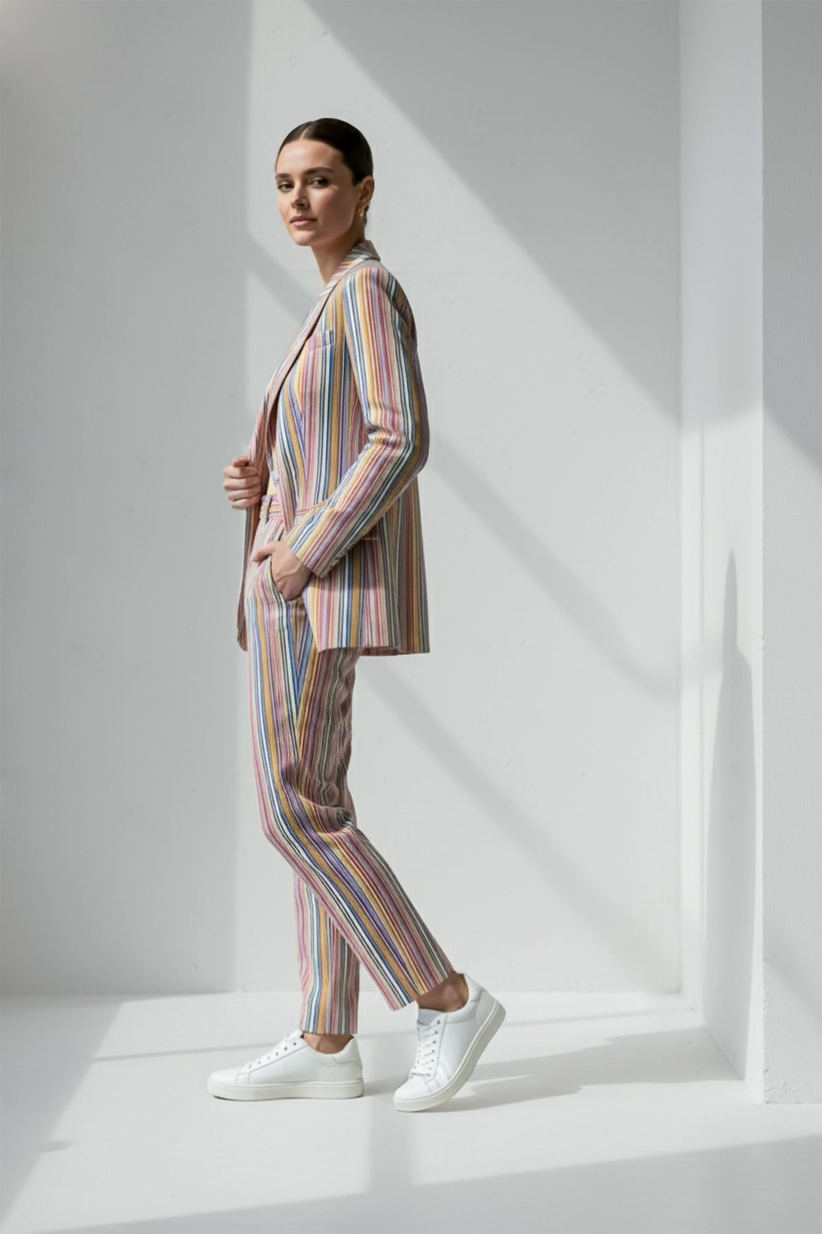 Person wearing a multicolored striped Linen suit standing against a white background