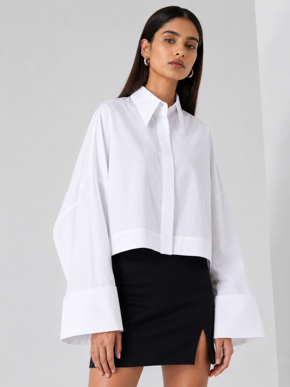 Woman wearing a white shirt and black skirt on a plain background