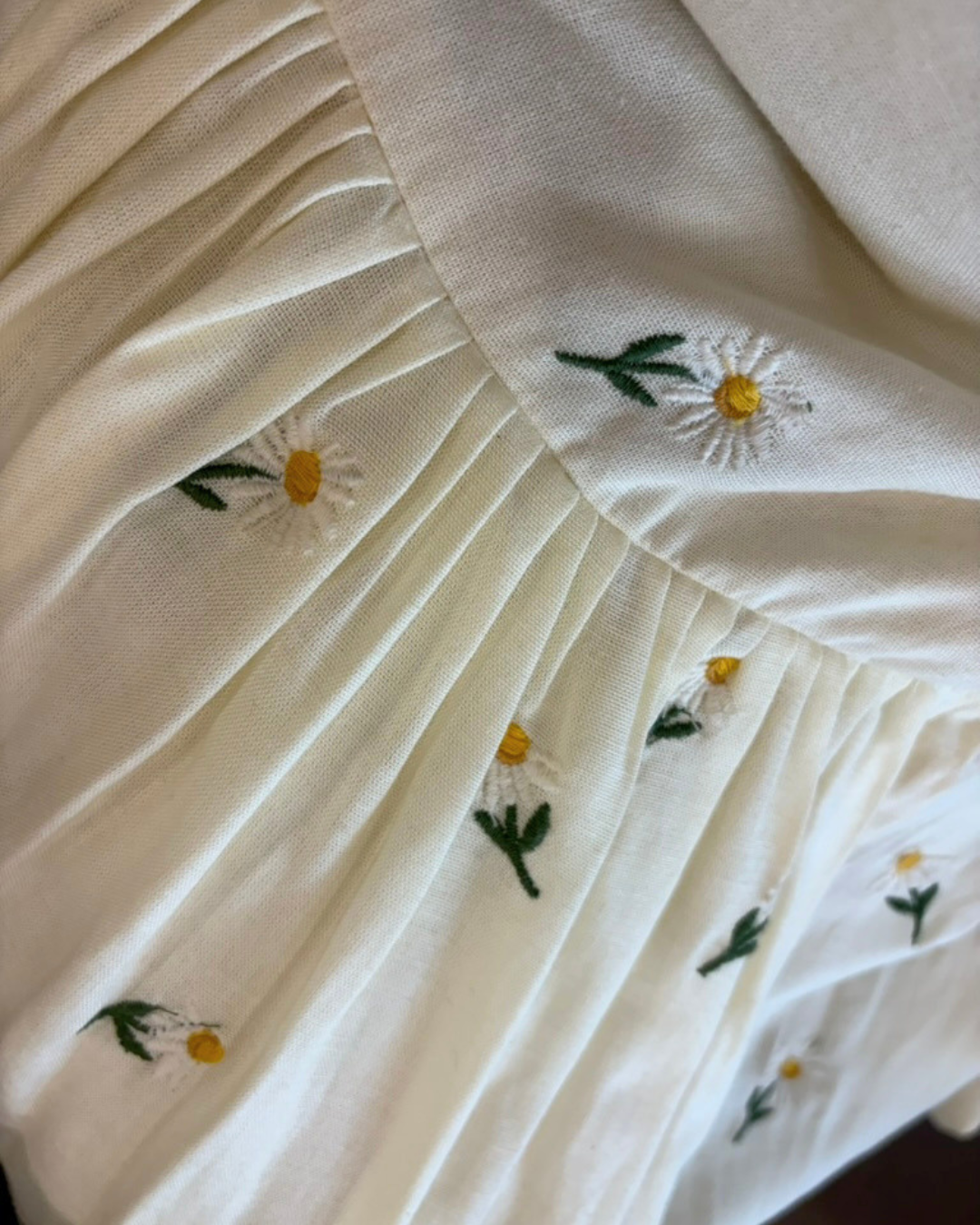 Close-up of daisy embroidery on linen fabric dress