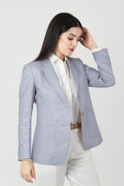 Woman wearing a light gray hemp blazer over a white shirt on a plain background