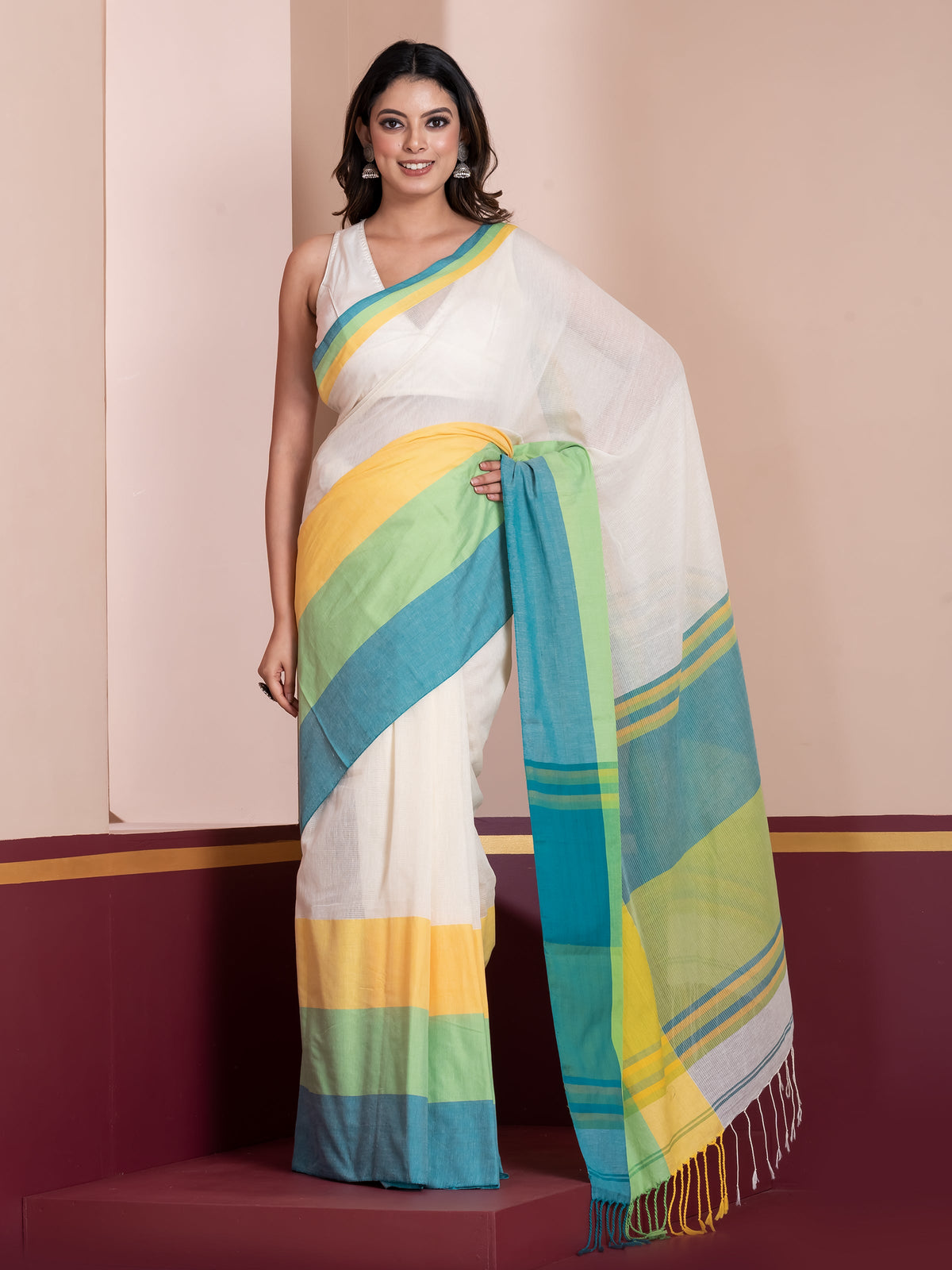 A woman modeling a traditional khaadi cotton saree with a white body and multicolored stripes and border.