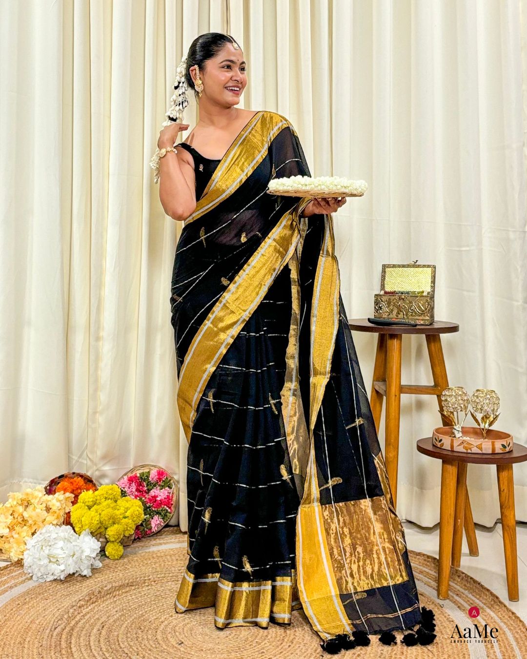 Women wearing handcrafted black mulmul cotton saree with golden border, styled for festive and cultural occasions