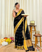 Women wearing handcrafted black mulmul cotton saree with golden border, styled for festive and cultural occasions