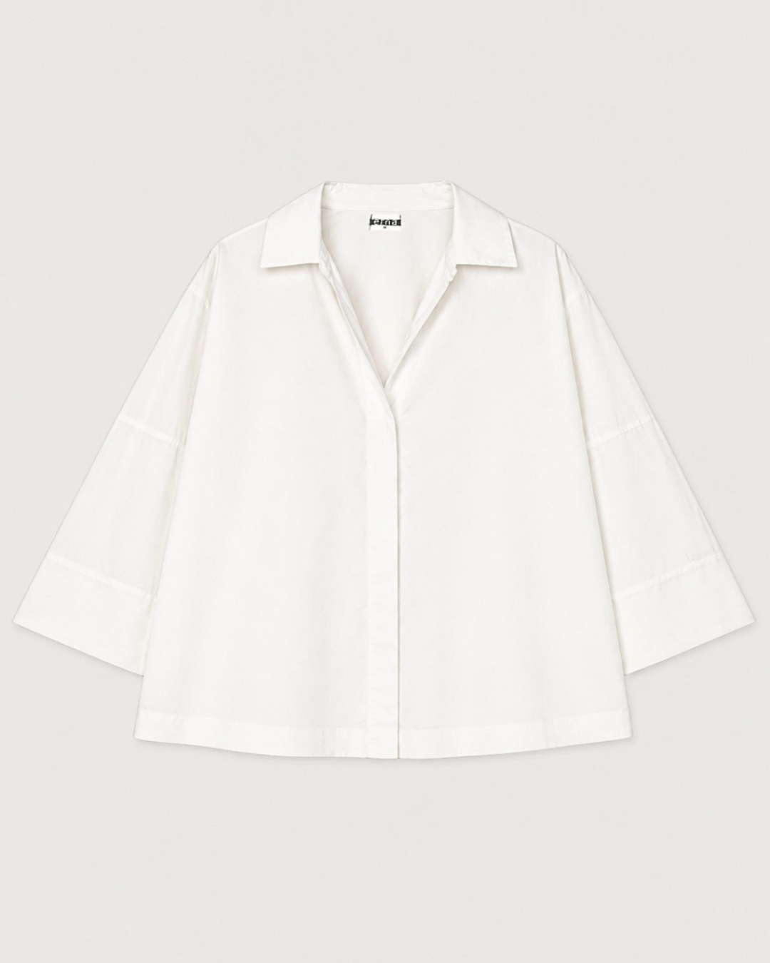 White blouse with a brand label on a light gray background