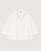 White blouse with a brand label on a light gray background