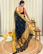 Women wearing handcrafted black mulmul cotton saree with golden border, styled for festive and cultural occasions