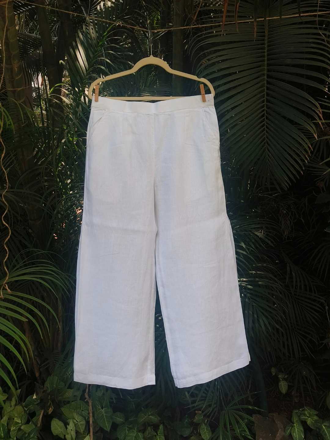 Vianca Pants- 100% Hemp | Jhultaru. Fabric: 100% Hemp  Color: Classic White. Side seam pleat detail. Wide-leg silhouette. Mid-rise with back elastic. Pockets on both sides. Breathable, lightweight, eco-friendly and sustainable- Vianca Pants in 100% hemp with wide legs and soft pleats at the side seams. Clean, breathable, and made for slow, intentional living.