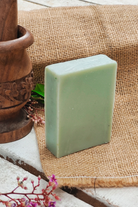 Lavender handmade cold process soap bar standing on natural jute cloth with wooden decor elements, eco-friendly herbal soap by Almitra Sustainable for relaxing aromatherapy, soft cleansing and sustainable skincare routine.