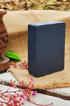 Almitra Sustainable handmade charcoal soap bar placed on natural fabric with botanical decor, cold processed detox soap for face and body.