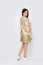 Woman wearing a floral linen blazer and beige skirt on a white background