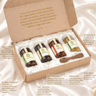An open kraft paper gift box containing four honey jars arranged in white foam inserts, with surrounding callout text labels describing each honey variety and product features. No person, animal, or real environment is present; this is a styled product presentation, so subject_type is Product/Packaging.