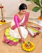 Woman in traditional attire performing a ritual with flowers and a lamp on a woven mat.
