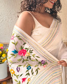 Elegant white embroidered saree with intricate floral thread work and soft graceful drape