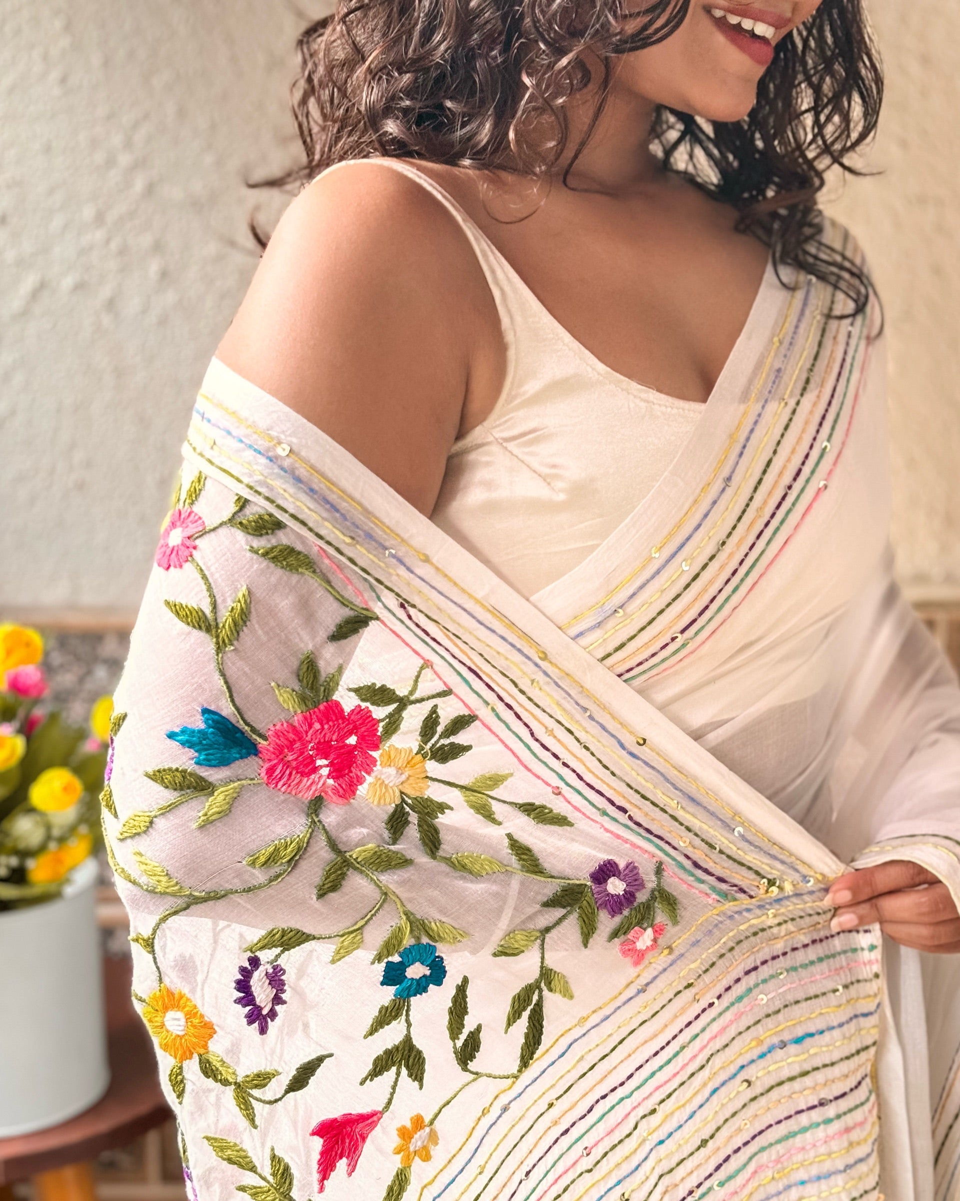Elegant white embroidered saree with intricate floral thread work and soft graceful drape