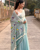 Traditional Indian cyan mulmul saree with detailed embroidery work
