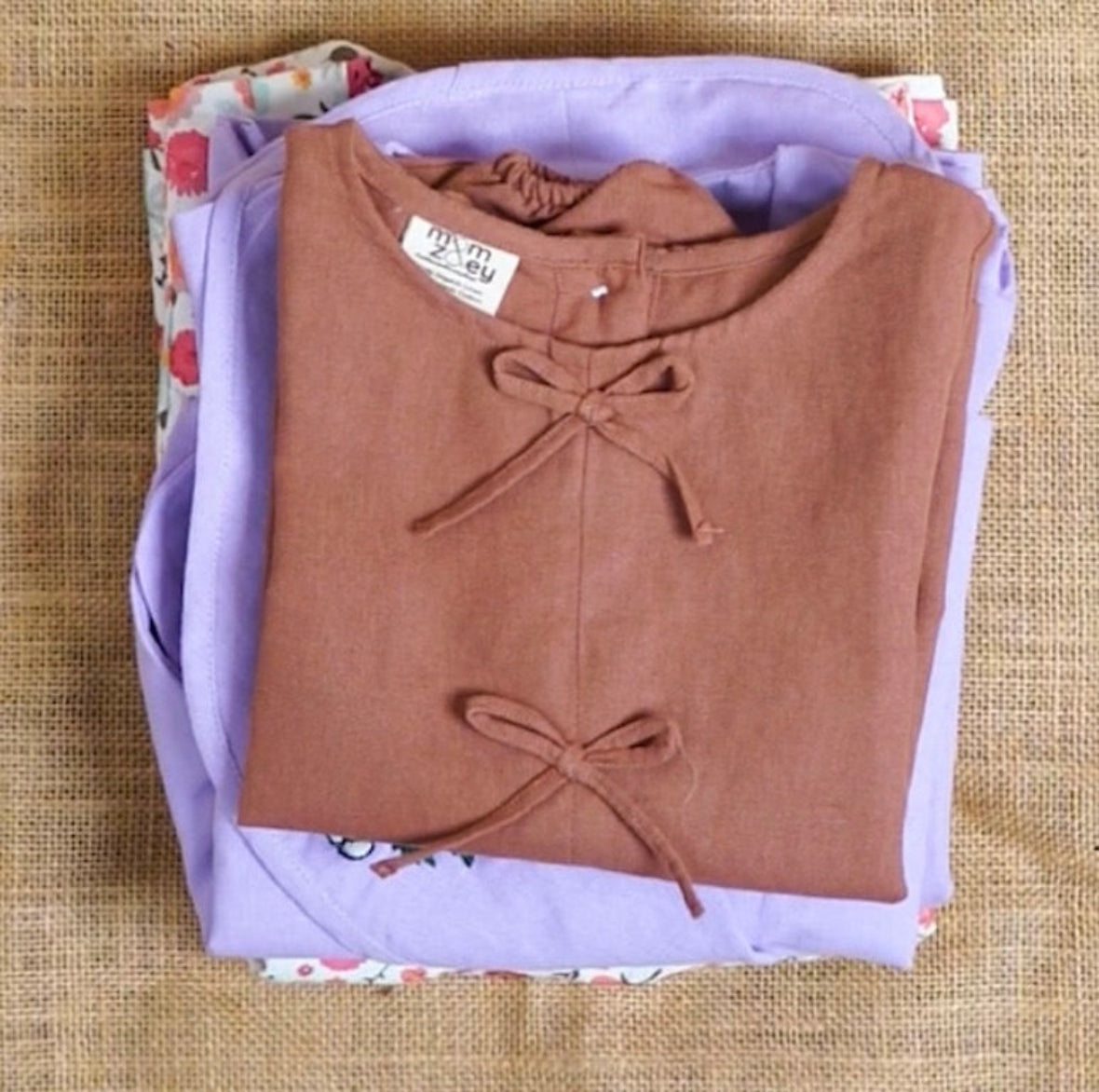 Folded brown shirt with a bow on a purple garment on a textured surface