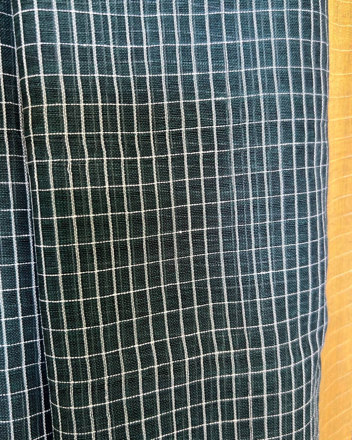 Close-up of green checkered handloom cotton Shopaame saree with a yellow border