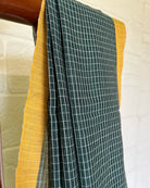 Green checkered handloom cotton saree with yellow border on a white background