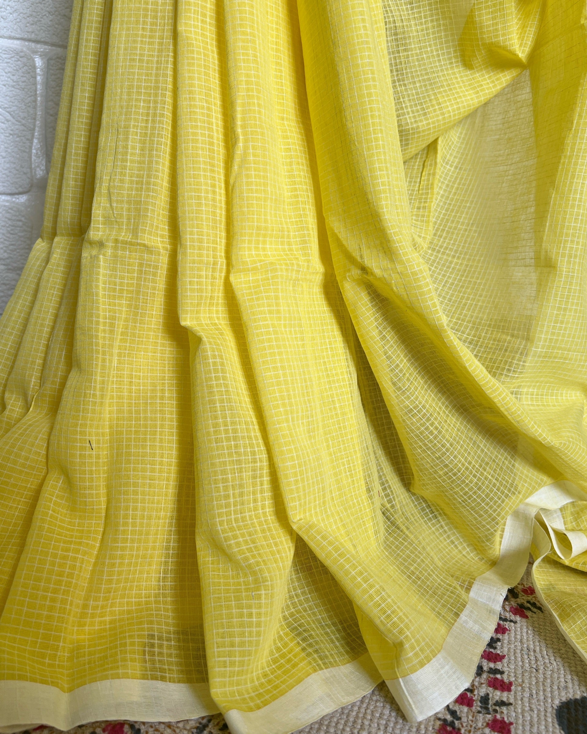 Yellow handloom saree by Shopaame with a checkered pattern on a textured surface
