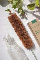 Coconut fiber bottle brush with metal handle for sustainable and non-toxic cleaning of reusable glass bottles.
