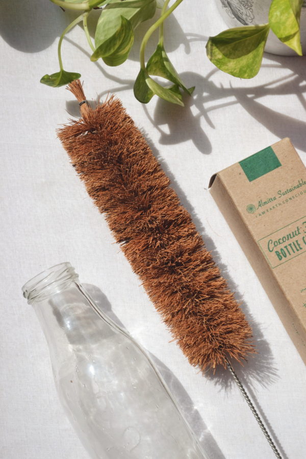 Coconut fiber bottle brush with metal handle for sustainable and non-toxic cleaning of reusable glass bottles.