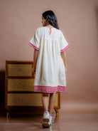 Women wearing off-white handwoven kala cotton tunic dress with red trims. adorn with hand embroidery, this dress features half sleeves, gathered yoke and two roomy pockets. Stylish, sustainable and made to be lived in.