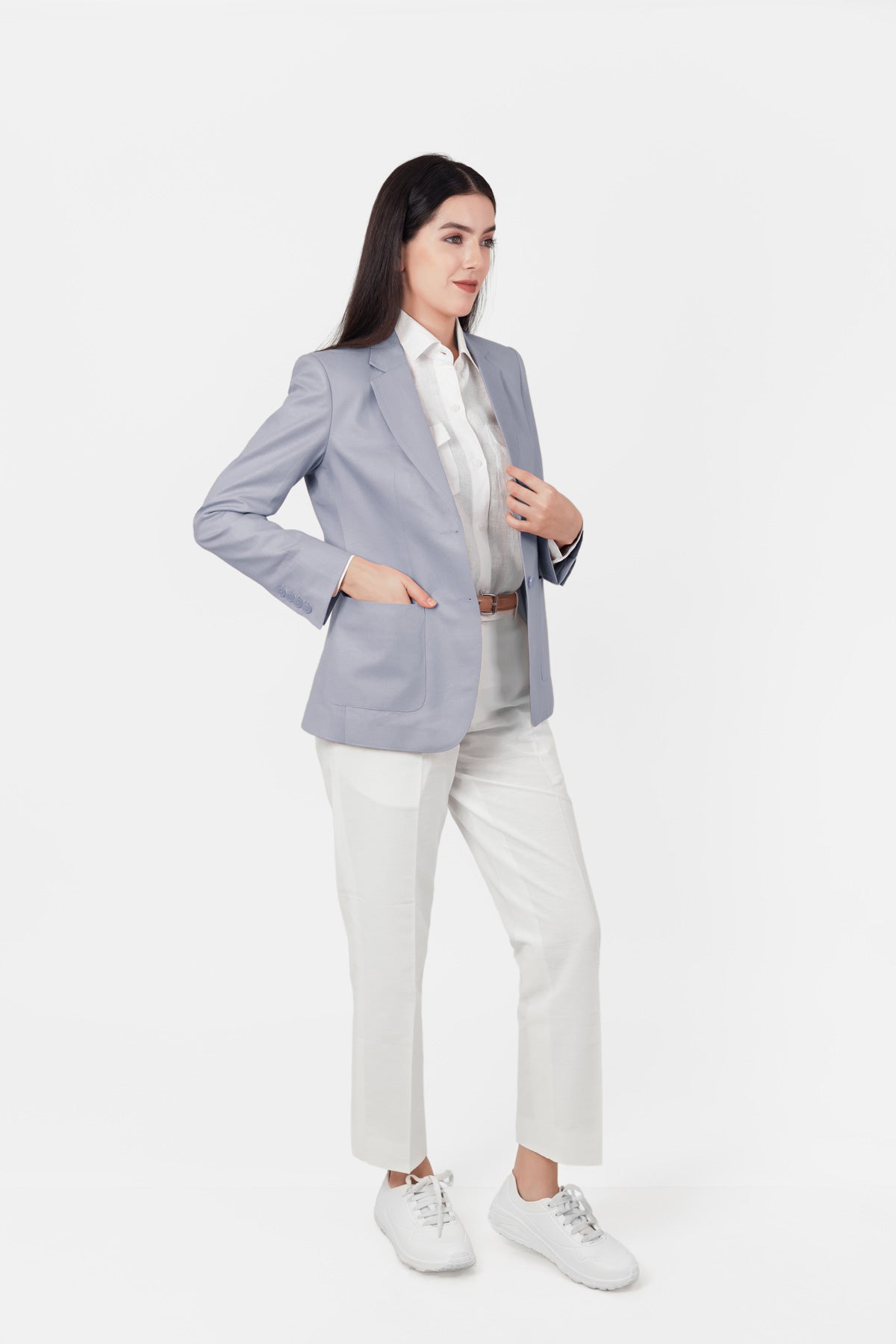Woman wearing a light gray hemp blazer, white shirt, and white pants on a white background