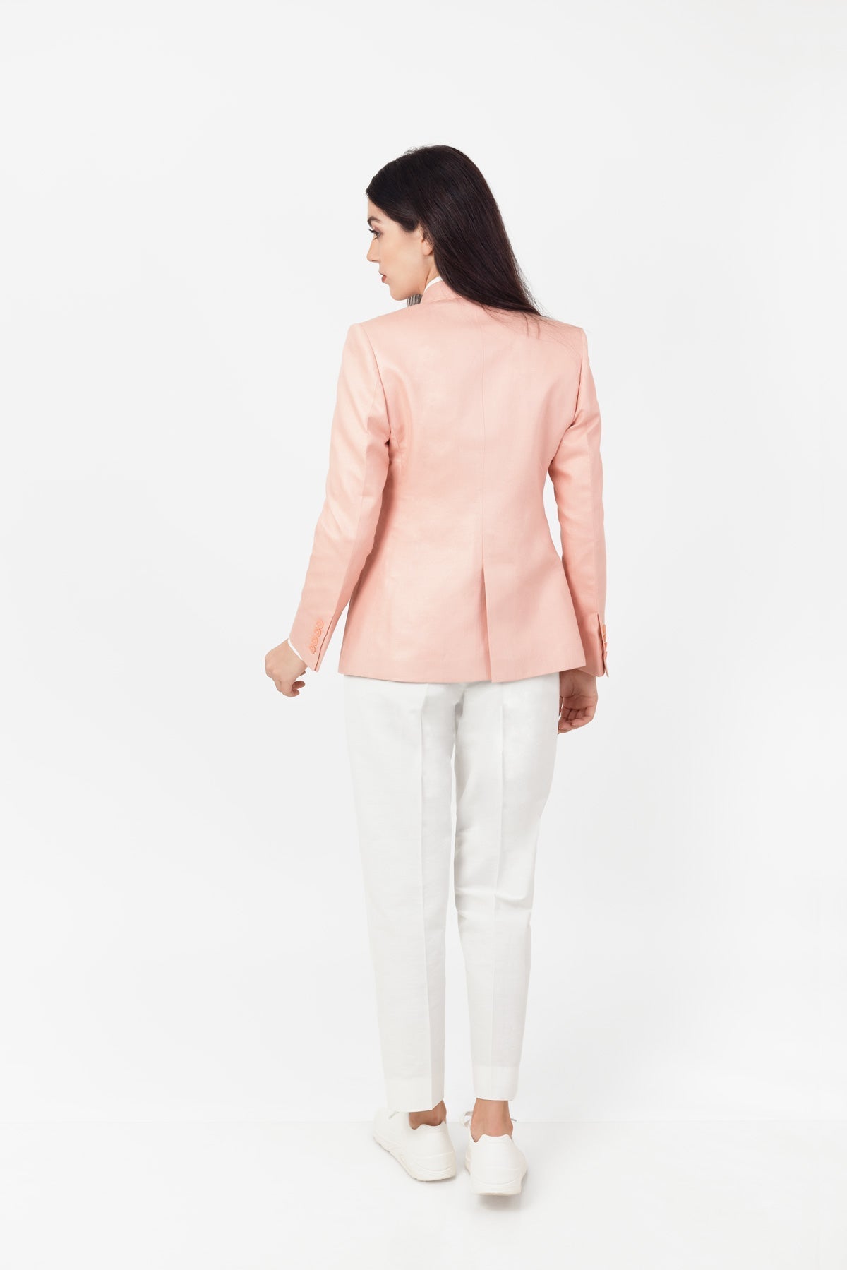 Woman wearing a light pink hemp blazer and white pants on a white background