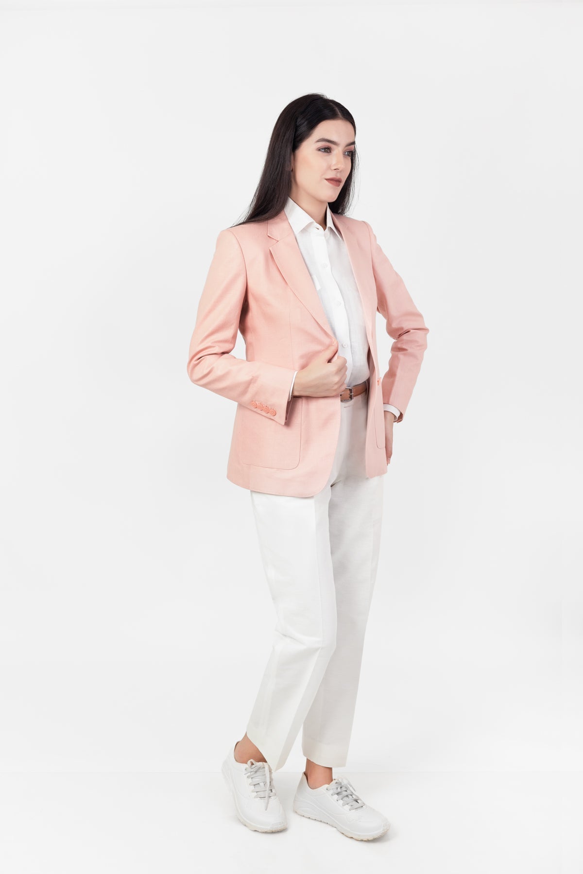 Woman wearing a pink hemp blazer, white shirt, and white pants on a white background