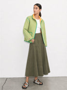 Woman wearing a green checkered jacket and olive green skirt on a white background