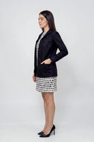 Woman wearing a black linen blazer with patch pockets over a monochrome printed dress, showcasing elegant sustainable women’s fashion.