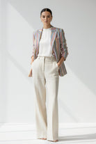 Woman wearing a striped Linen blazer and white pants on a plain background