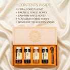 An open gift box of four honey jars and a wooden spoon on a cream satin background, with text listing contents: tribal forest honey, rakteel forest honey, Kashmiri white honey, sundarban forest honey, and a handcrafted wooden spoon.