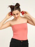 Gen Z woman wearing a soft, pink bamboo tube top, listening to music with red headphones and a playful hairstyle.